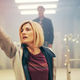 Jodie Whittaker's 13th Doctor raises her sonic screwdriver up to the air with a worried expression.